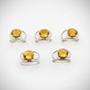 Silver rings with yellow gemstones on a white surface with floral decorations.